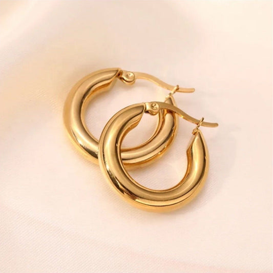 Gold hoop earrings on a light pink background